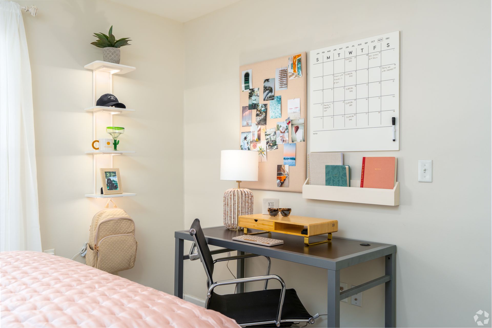 A modern desk setup in a corner room with shelves, corkboard, and calendar.
