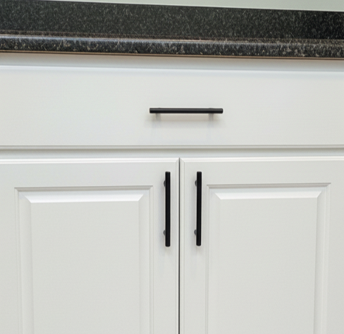 White cabinets with black hardware below a dark countertop.