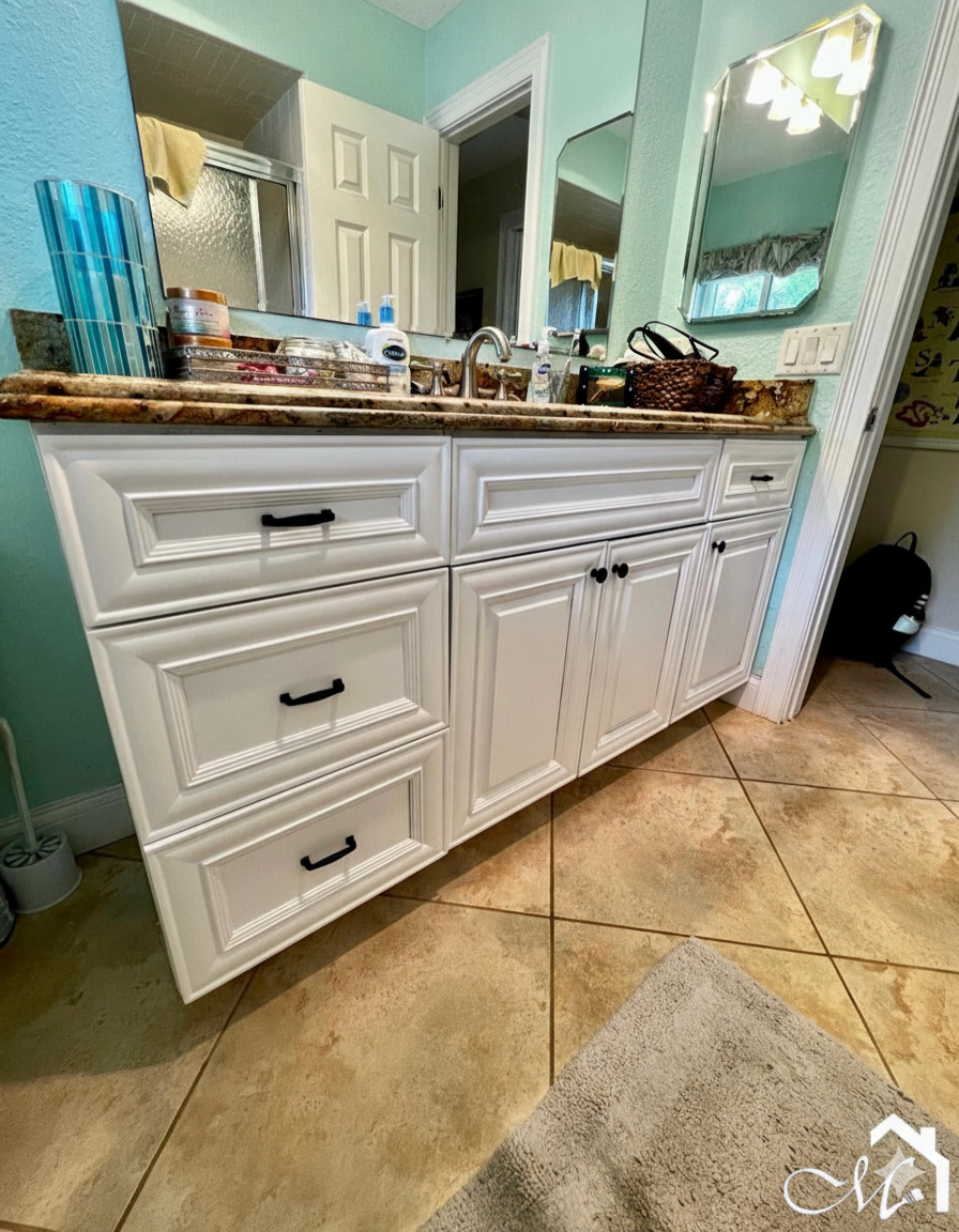White bathroom vanity with black hardware, granite countertop, and beige tile floor.