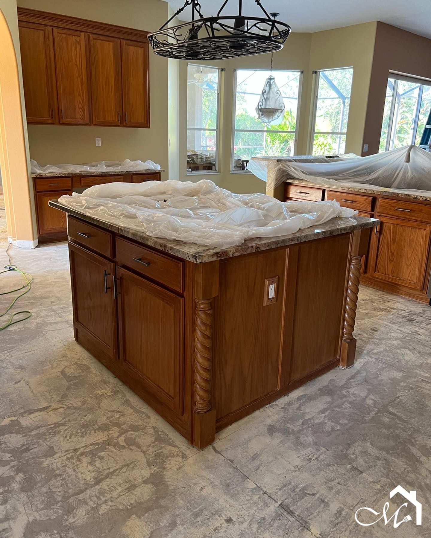 Kitchen island with granite countertop and wooden cabinets. Construction in progress.