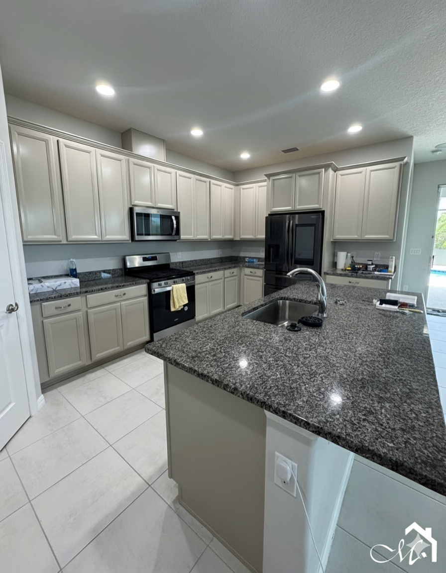 Beige kitchen with granite countertops, black appliances, and white tile flooring.