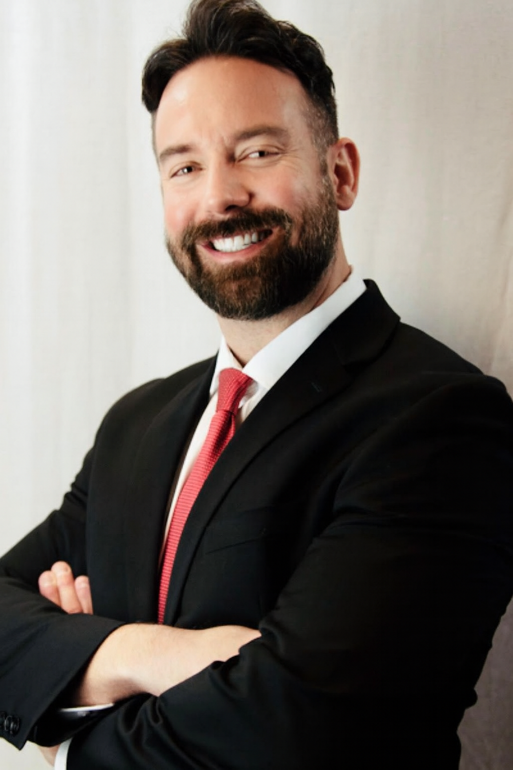 A man in a suit and tie is smiling for the camera