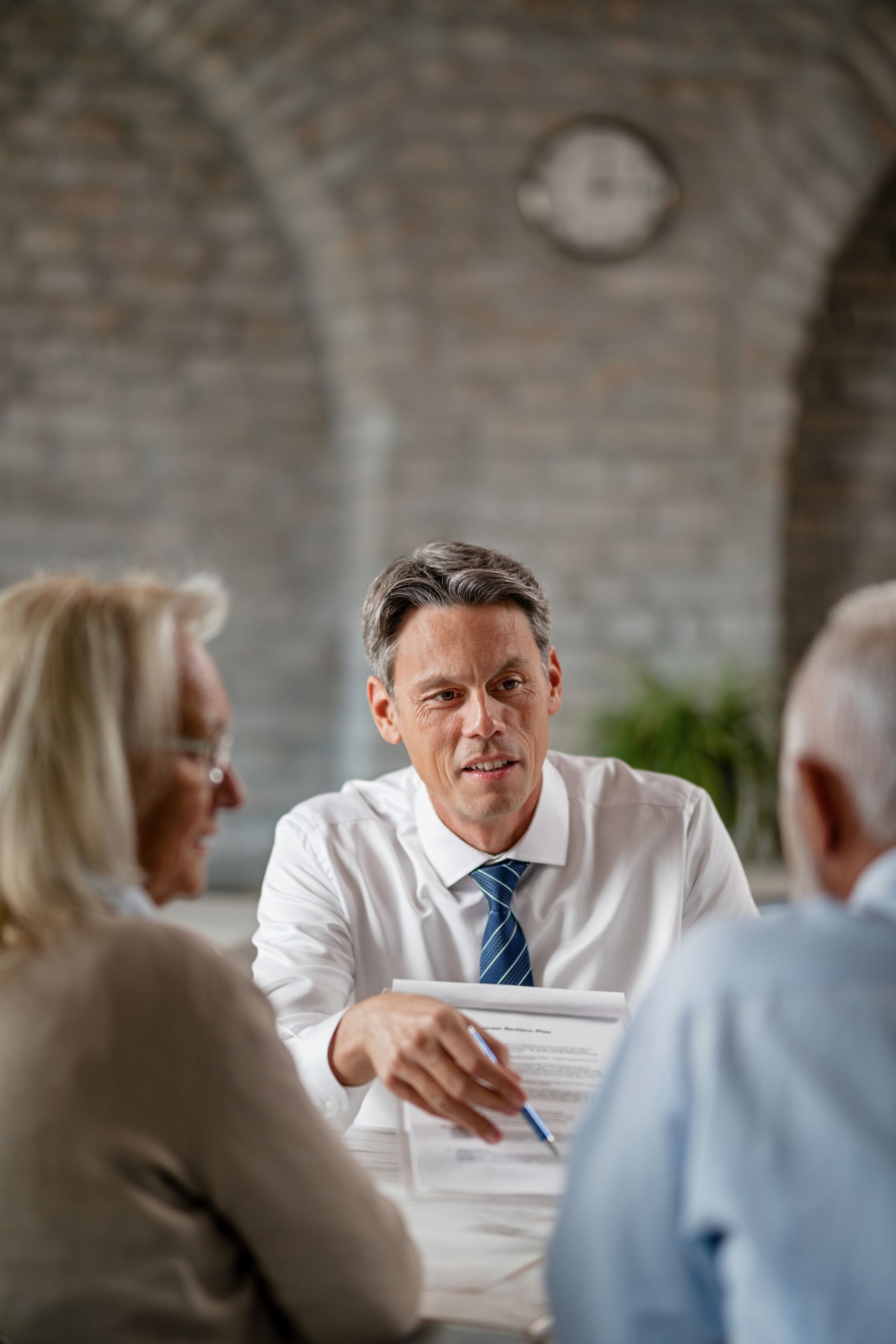 Financial advisor reviewing paperwork with senior couple at a table.