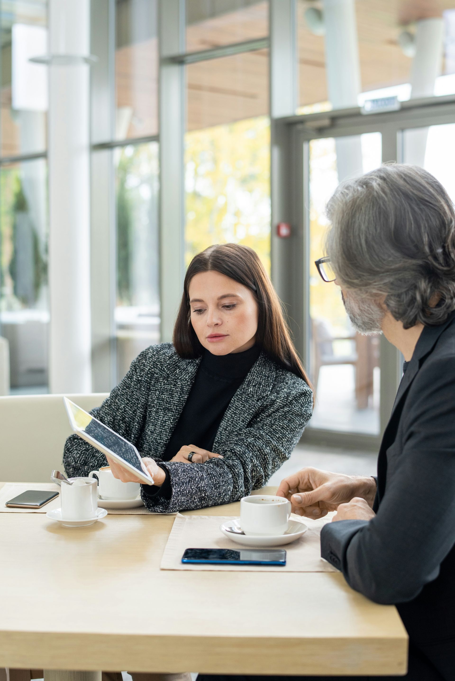 Woman and man reviewing documents at a wooden table in an office setting.