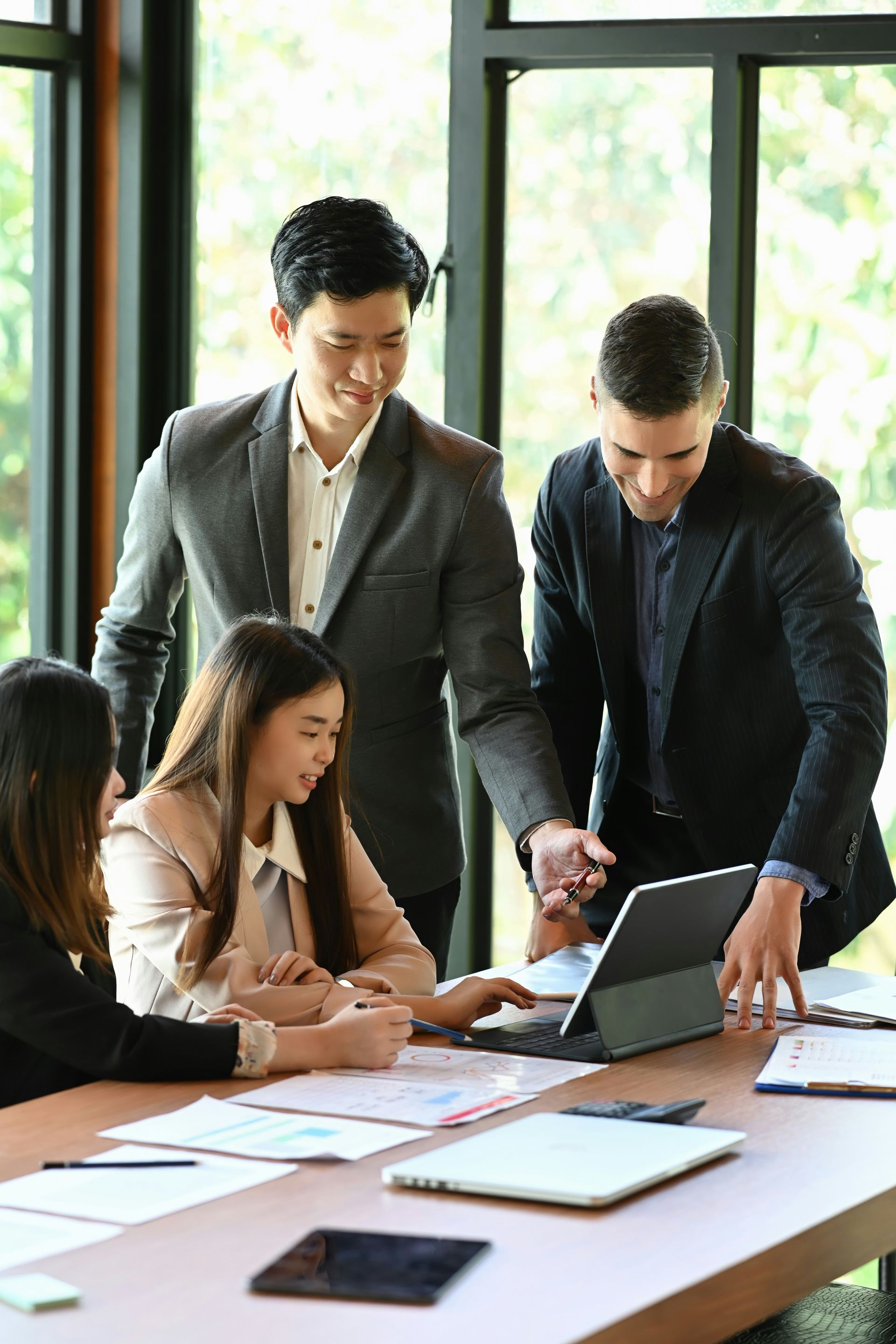 Senior couple reviews document with a professional at a table; indoor setting.