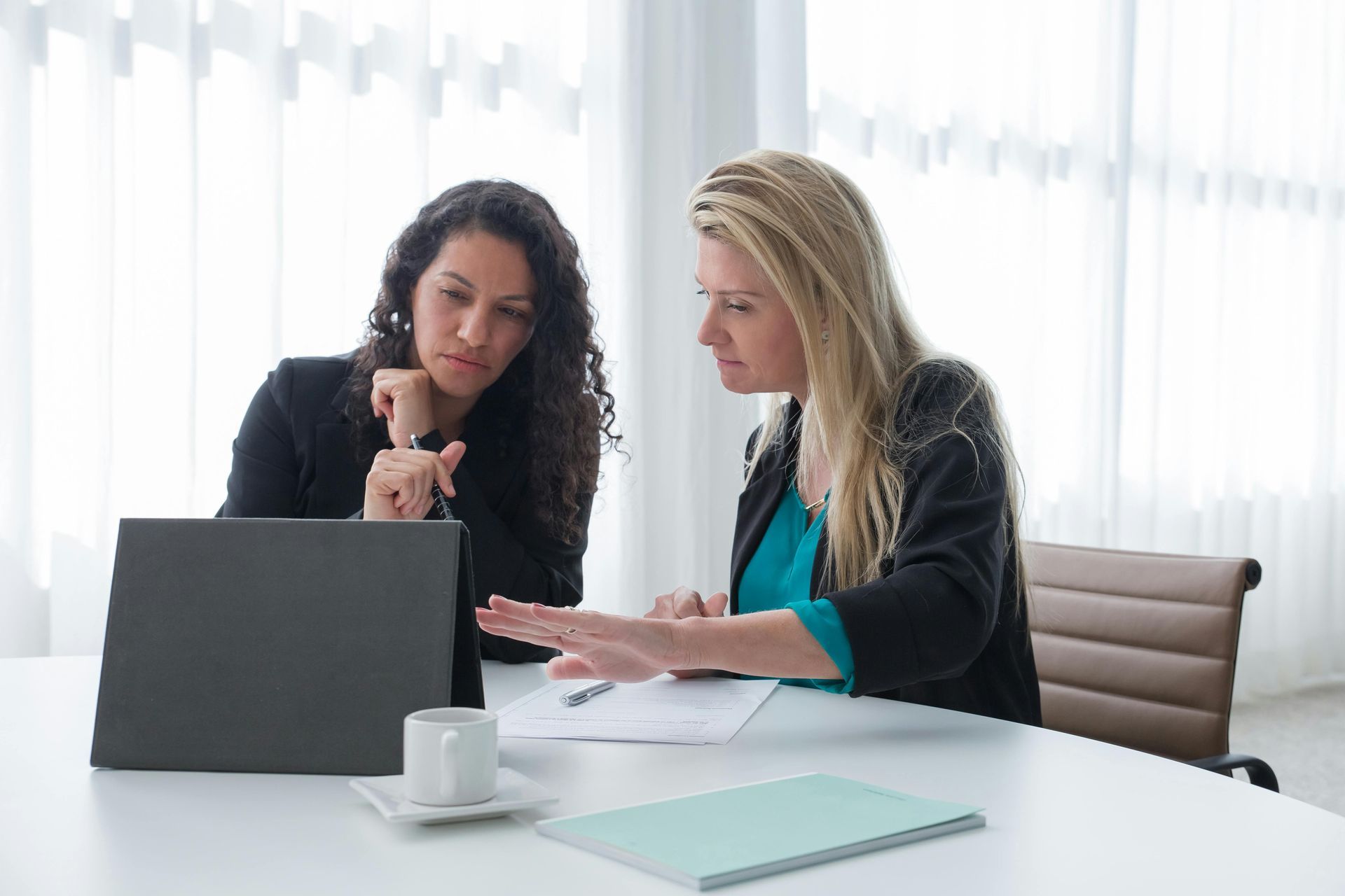Woman and man reviewing documents at a wooden table in an office setting.