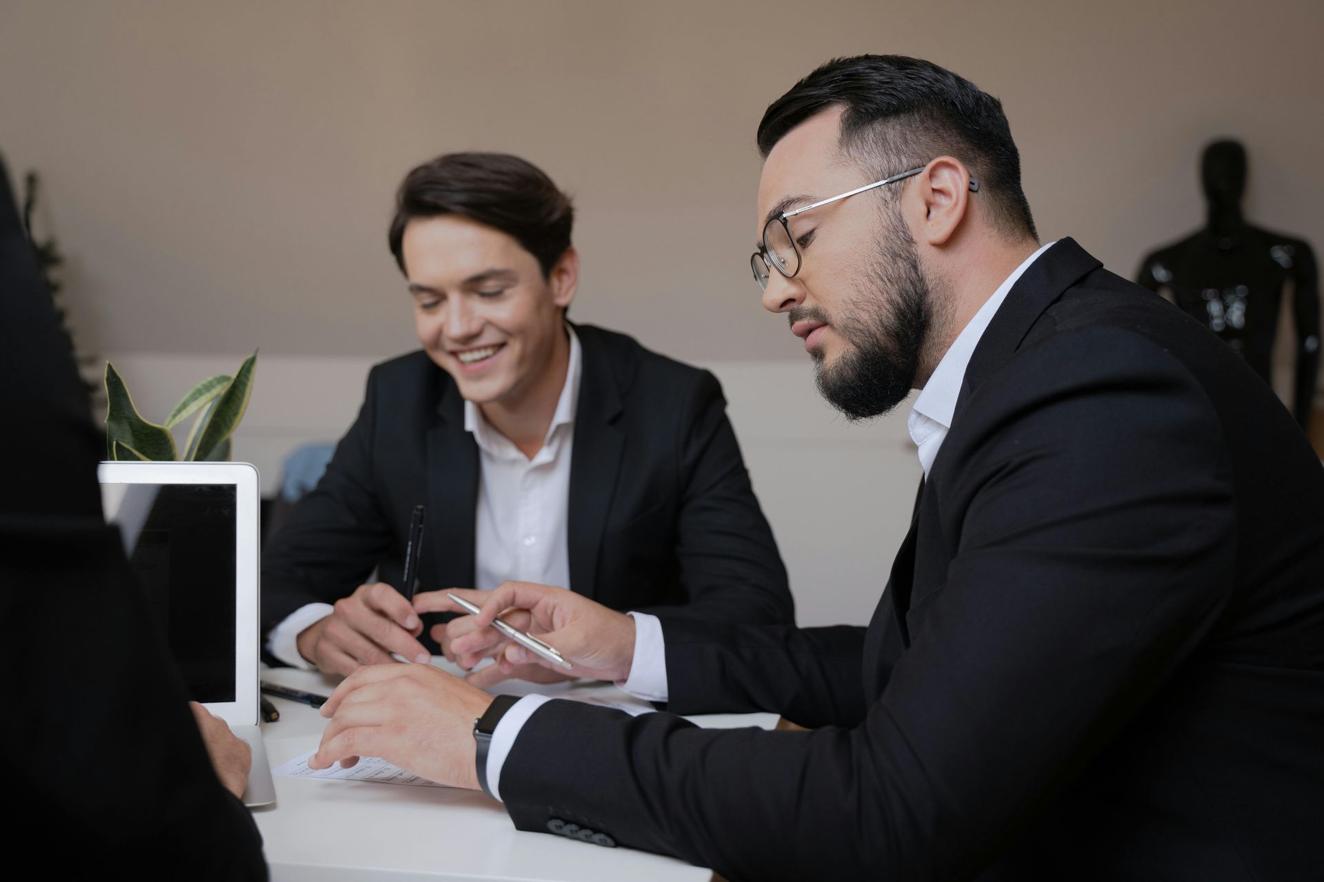 Senior couple reviews document with a professional at a table; indoor setting.