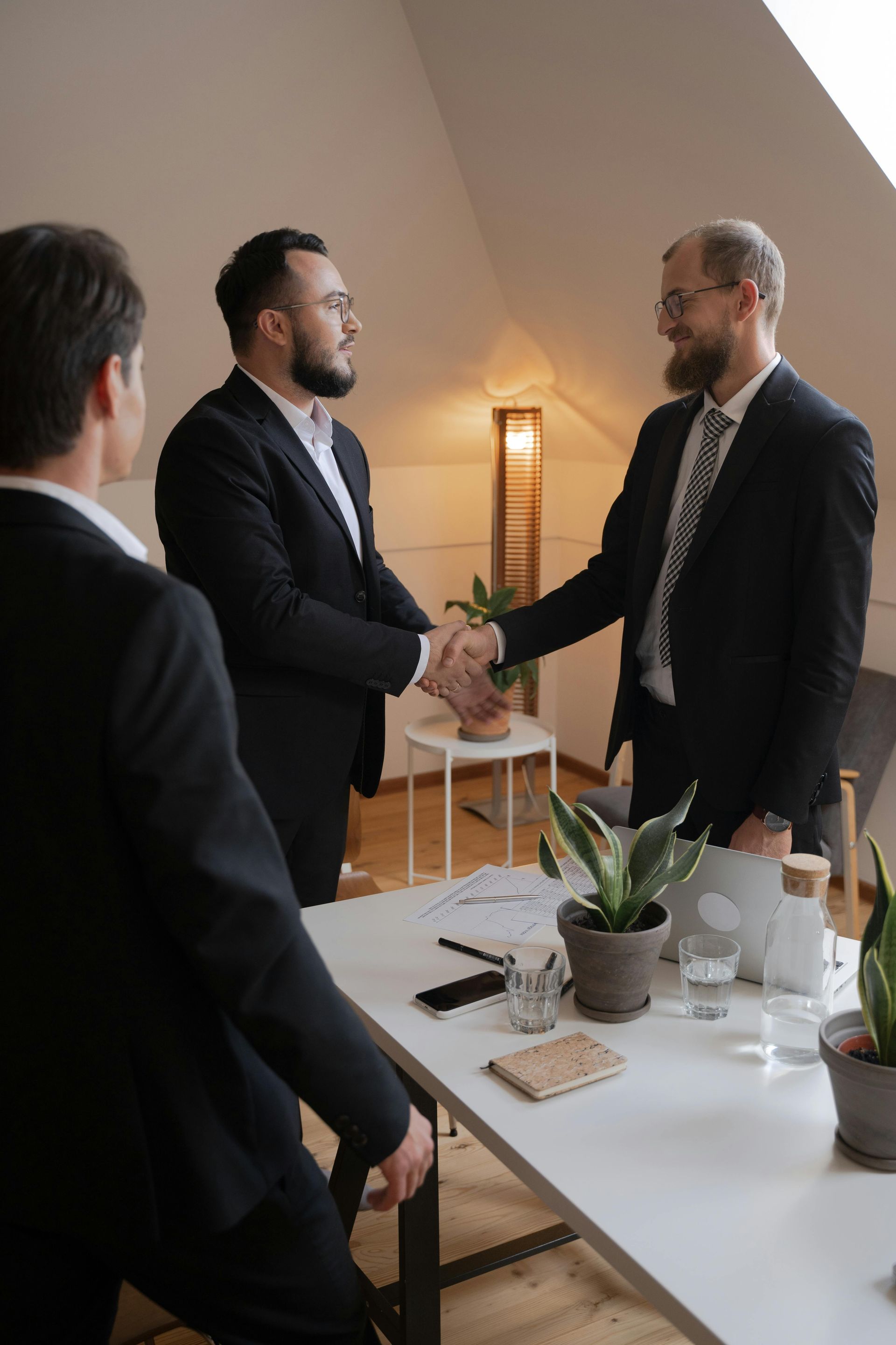 Senior couple reviews document with a professional at a table; indoor setting.