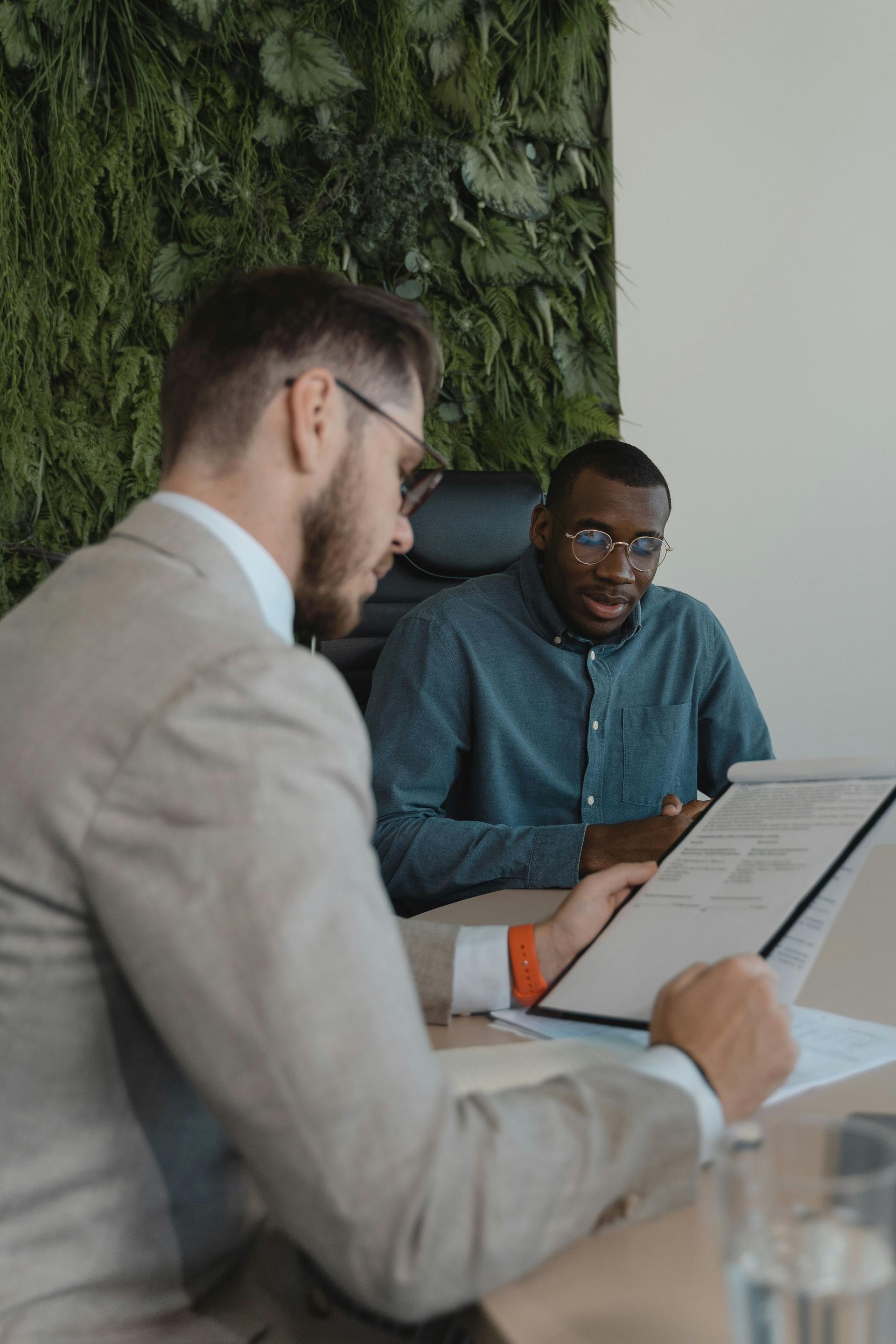 Senior couple reviews document with a professional at a table; indoor setting.