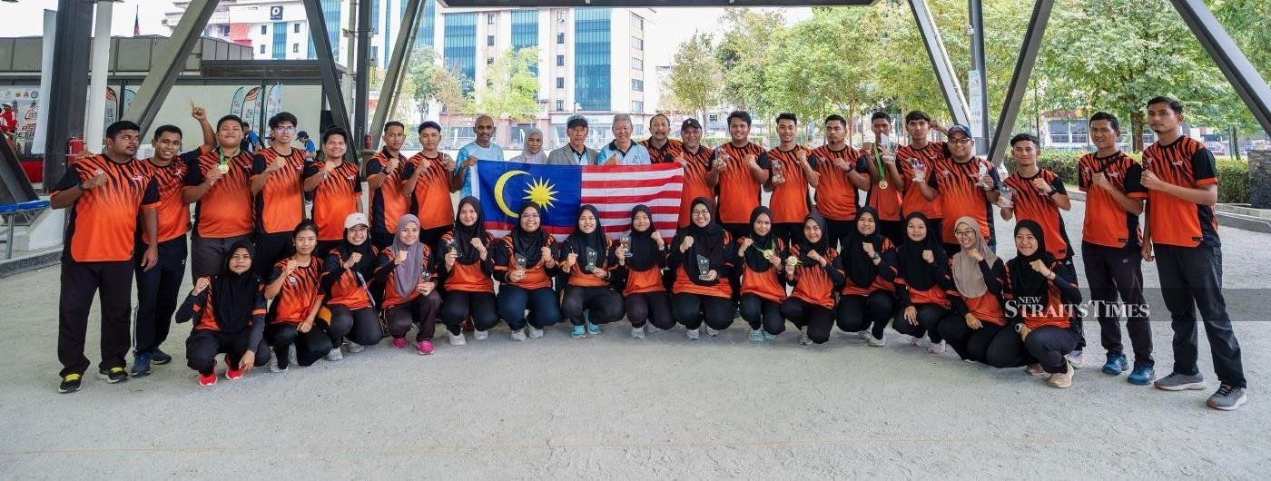 Malaysian team taking part in 6th Asia Petanque Championship 2025 posing with a large Malaysian flag.