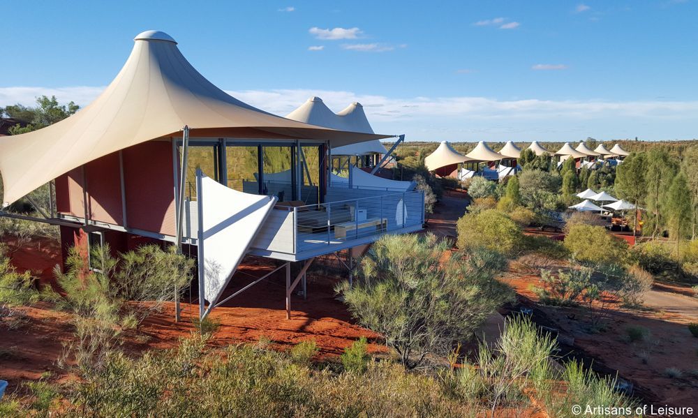 Luxury glamping tents on a red desert landscape, with a balcony, overlooking the surroundings.