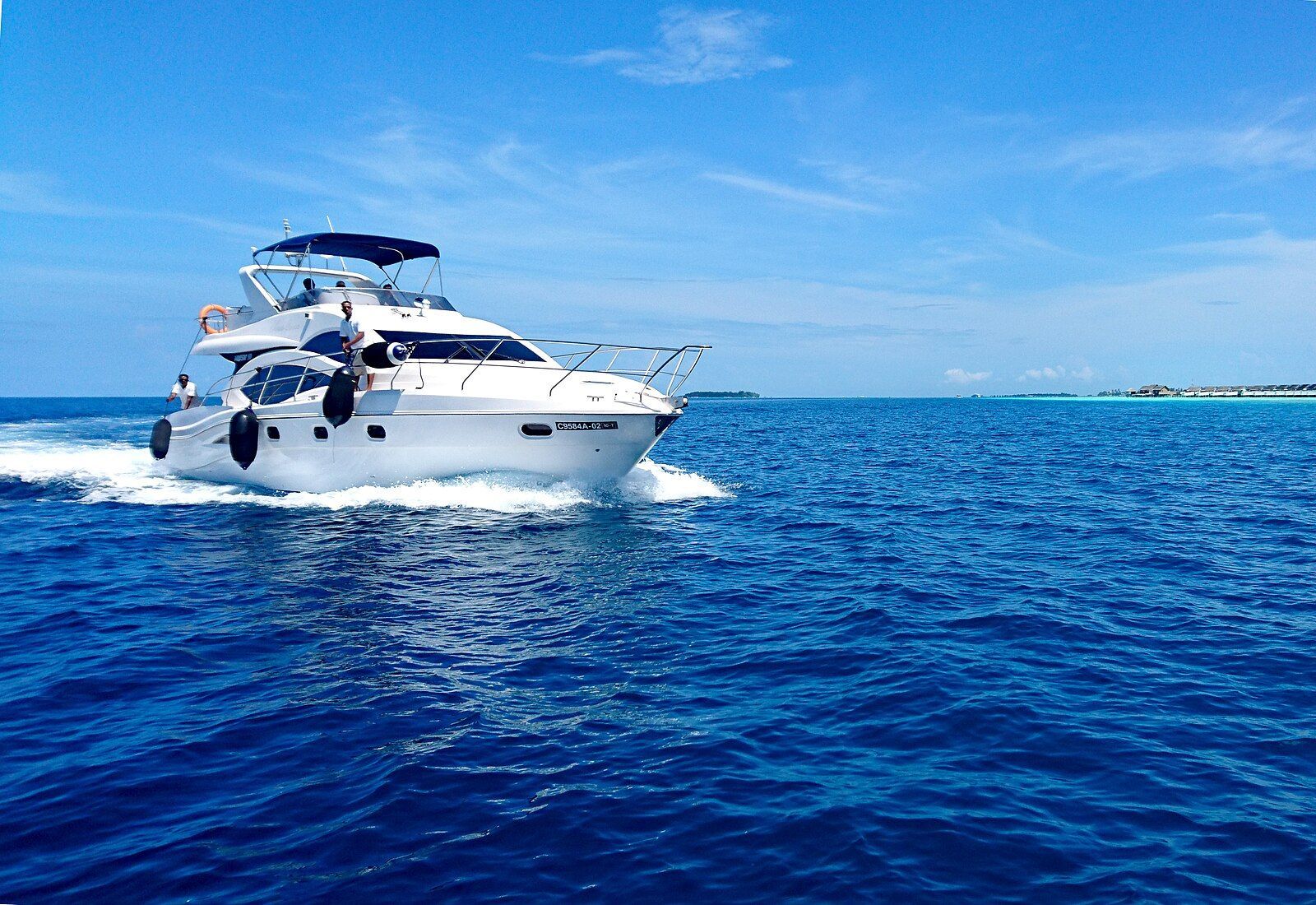 White yacht cruising on a vibrant blue ocean under a clear sky.