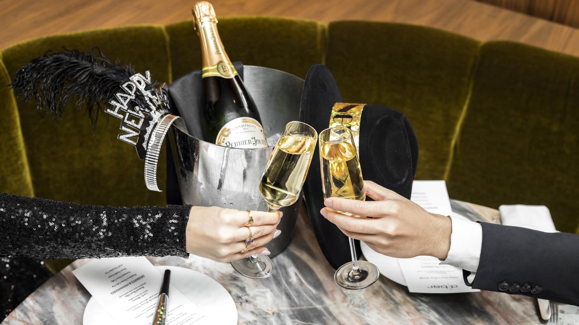 Two people toasting champagne flutes by a bucket with champagne and a hat. The Four Seasons Resort, Bora Bora