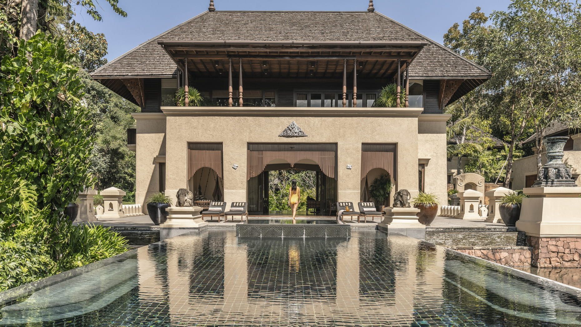 Overwater bungalows in turquoise water with a lush green mountain backdrop. The Four Seasons Resort, Chiang Mai exterior
