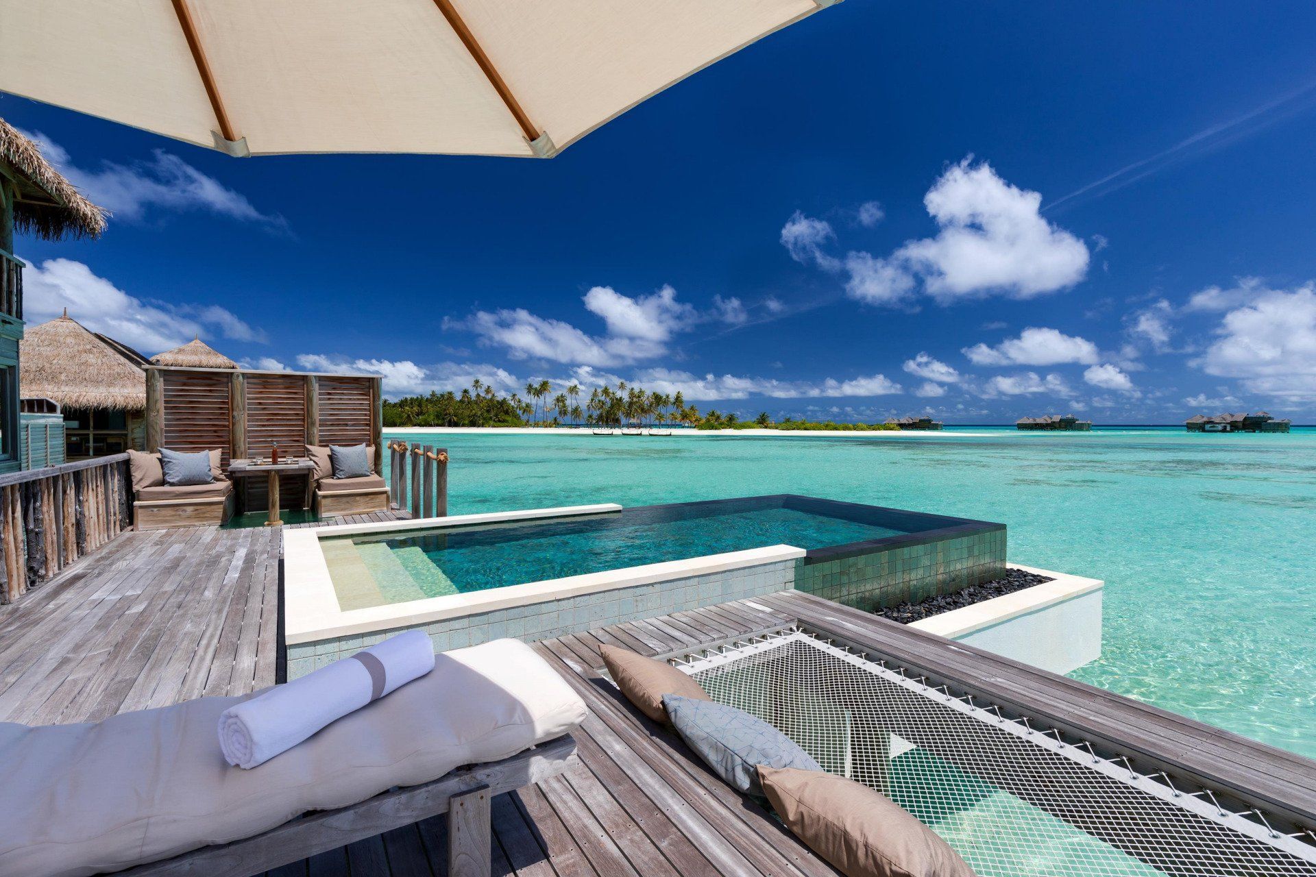 Luxury overwater villa with private pool, hammock, turquoise water, sunny day. Gili Lankanfushi