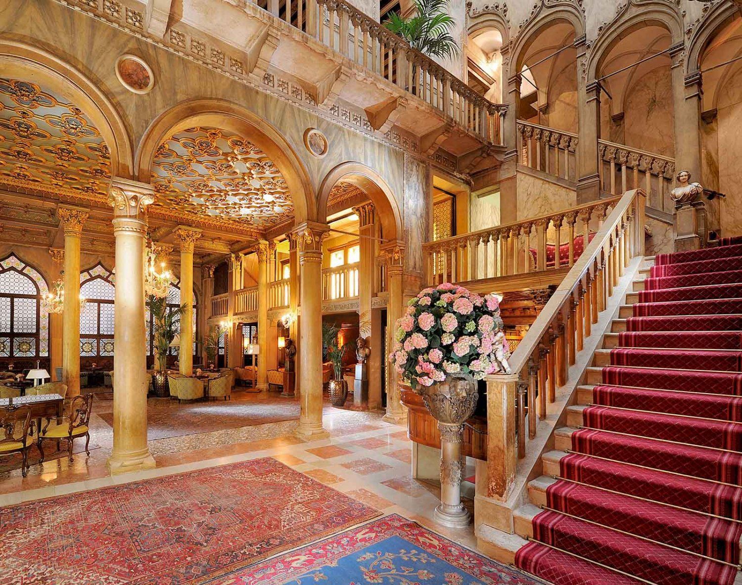 Ornate Venetian palace interior with red carpeted stairs and detailed ceilings. Hotel Danieli