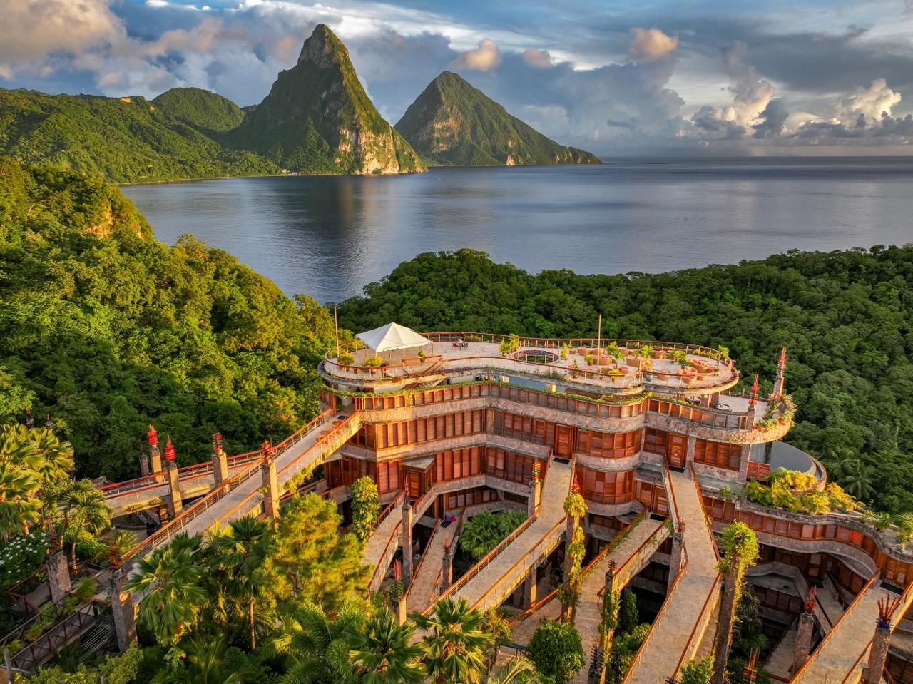 A luxurious hotel complex with elevated walkways nestled in lush green trees overlooking the Pitons in Saint Lucia. Jade Mountain, St Lucia