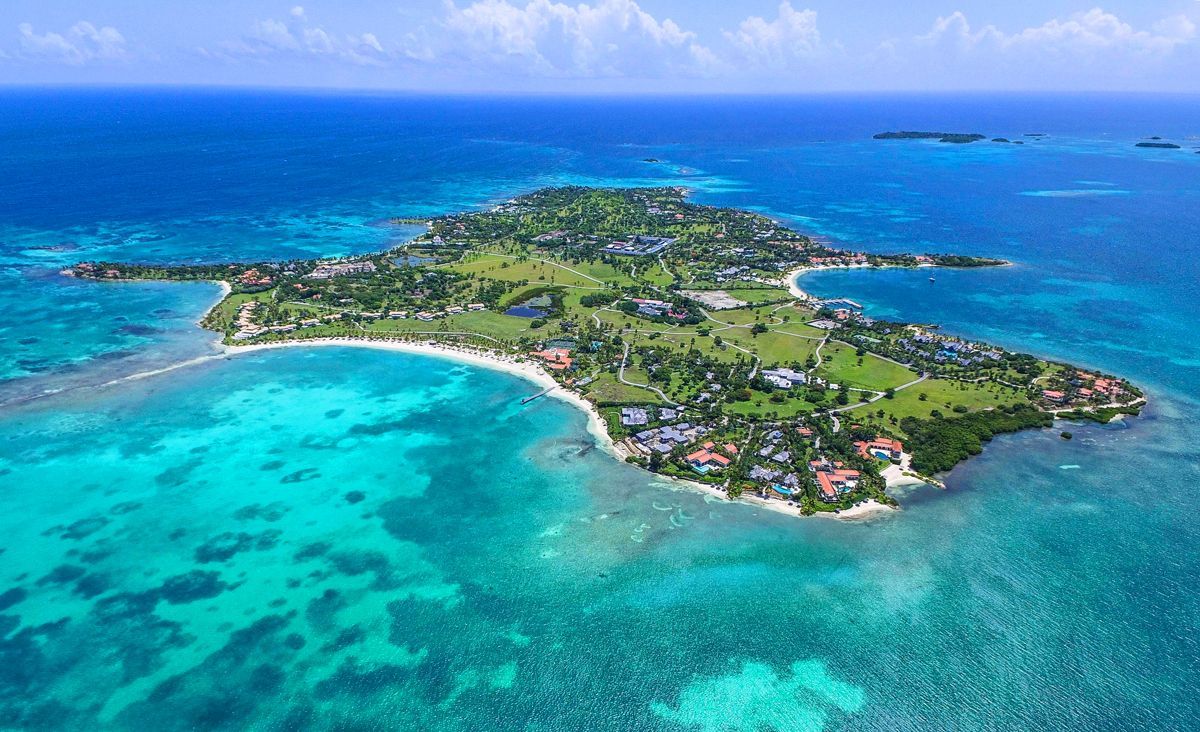 Aerial view of a tropical island with white sand beaches, turquoise water, and green vegetation.