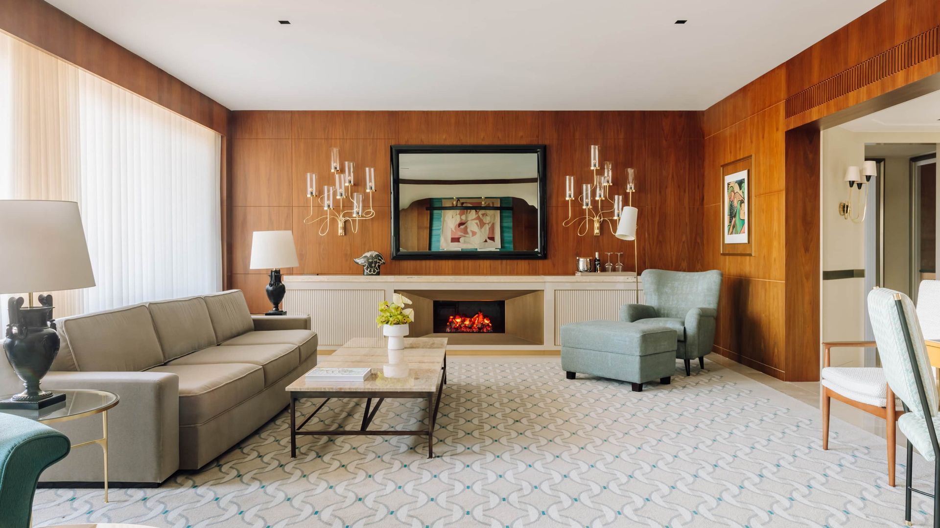 Modern living room with gray sofa, fireplace, wood-paneled walls, and large windows
