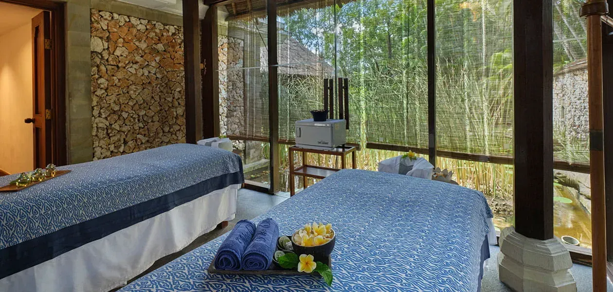 Spa treatment room with two massage tables facing a bamboo forest view. Oberoi, Bali