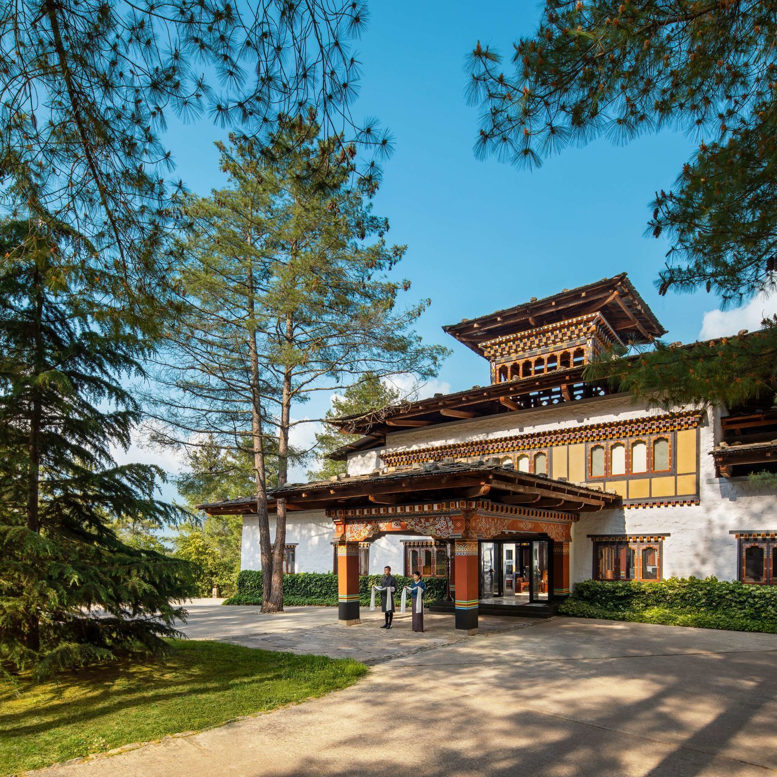 Hotel entrance with traditional Bhutanese architecture, nestled amidst trees and greenery. Bhutan Paro