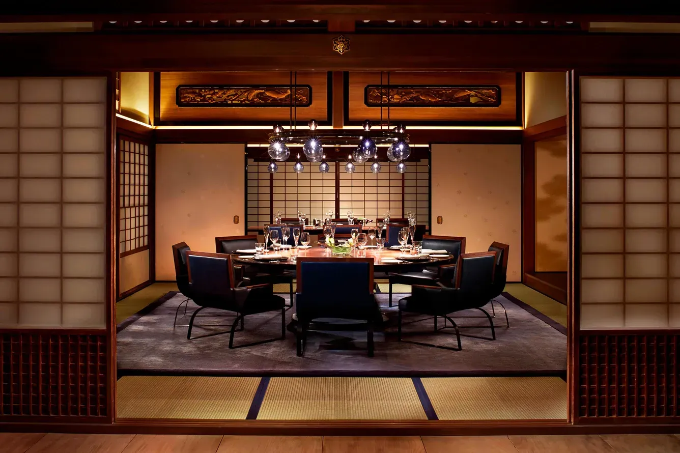 Japanese-style dining room with round table set for a meal, seen through shoji screens.