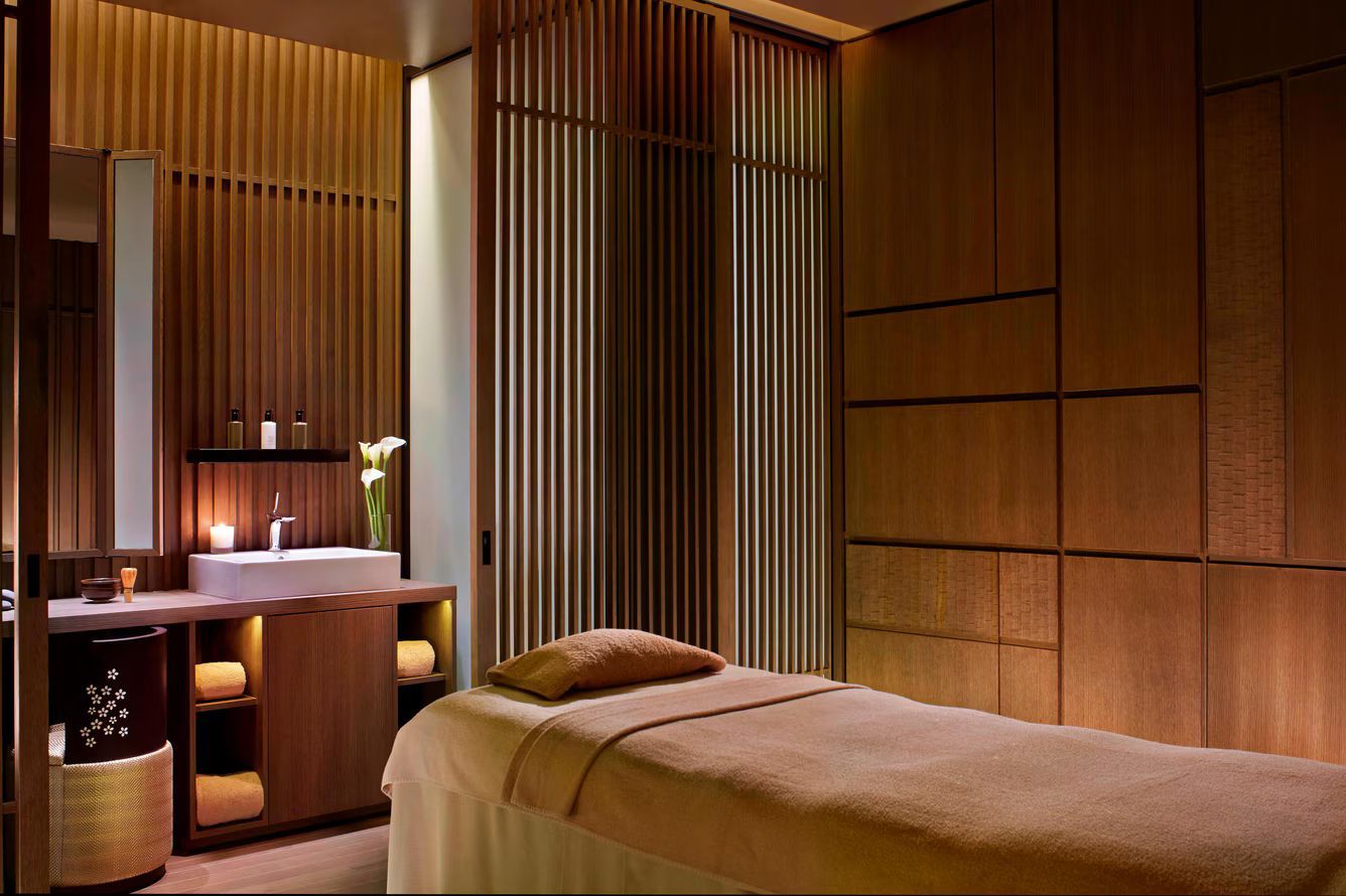 Spa room with massage table, wooden paneling, and sink area.