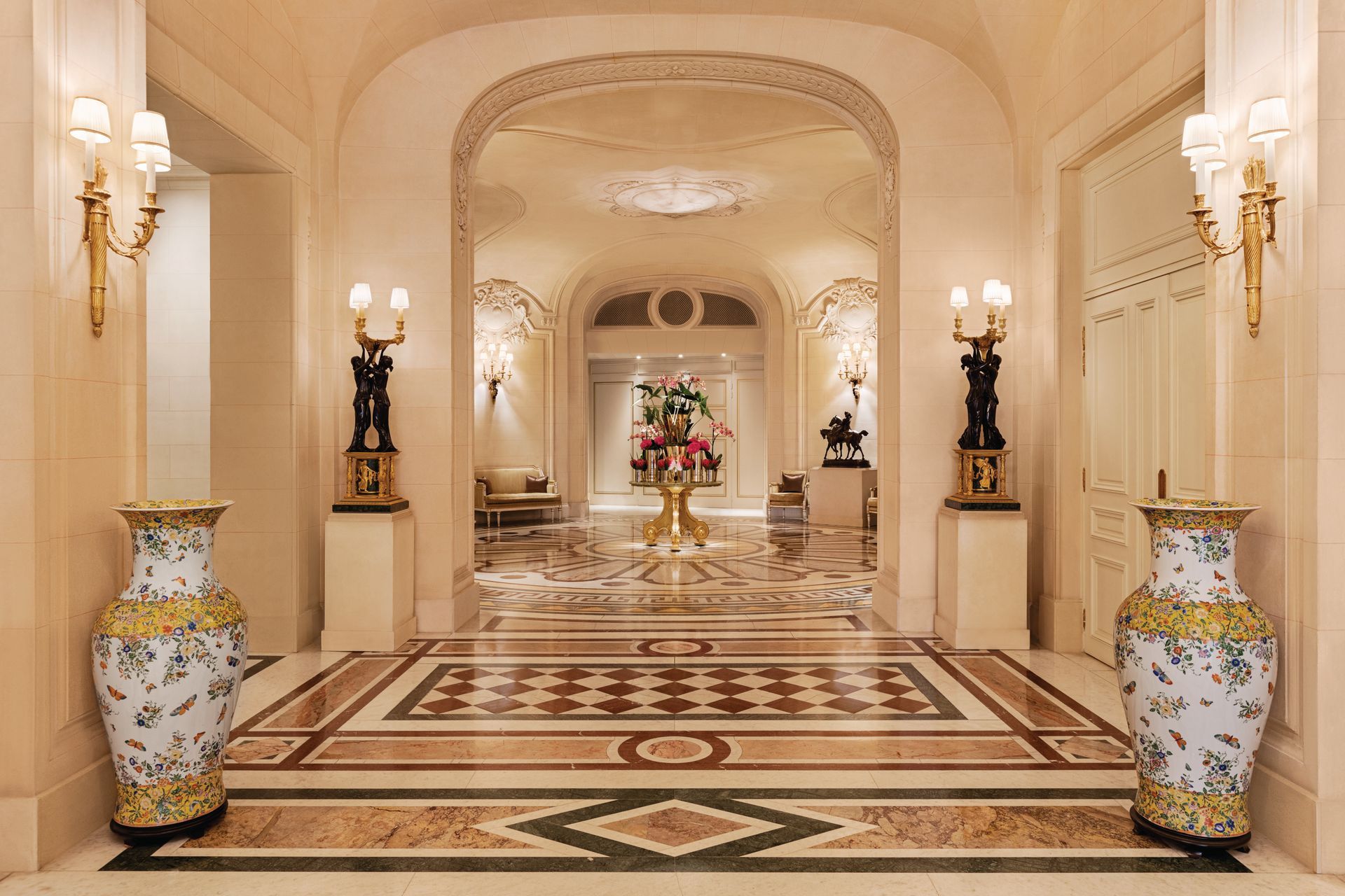 Elegant hallway with ornate marble floor, archways, vases, sconces. Shangri-La Paris