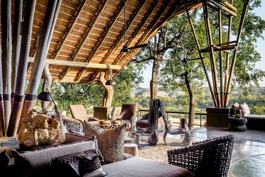 Open-air lounge with woven furniture, wood beams, and a view of trees and landscape. Singita Boulders Lodge (Sabi Sands)
