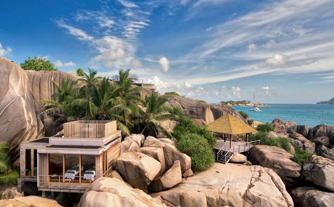 Luxury resort on rocky coast with turquoise ocean under blue sky. Six Senses Zil Pasyon