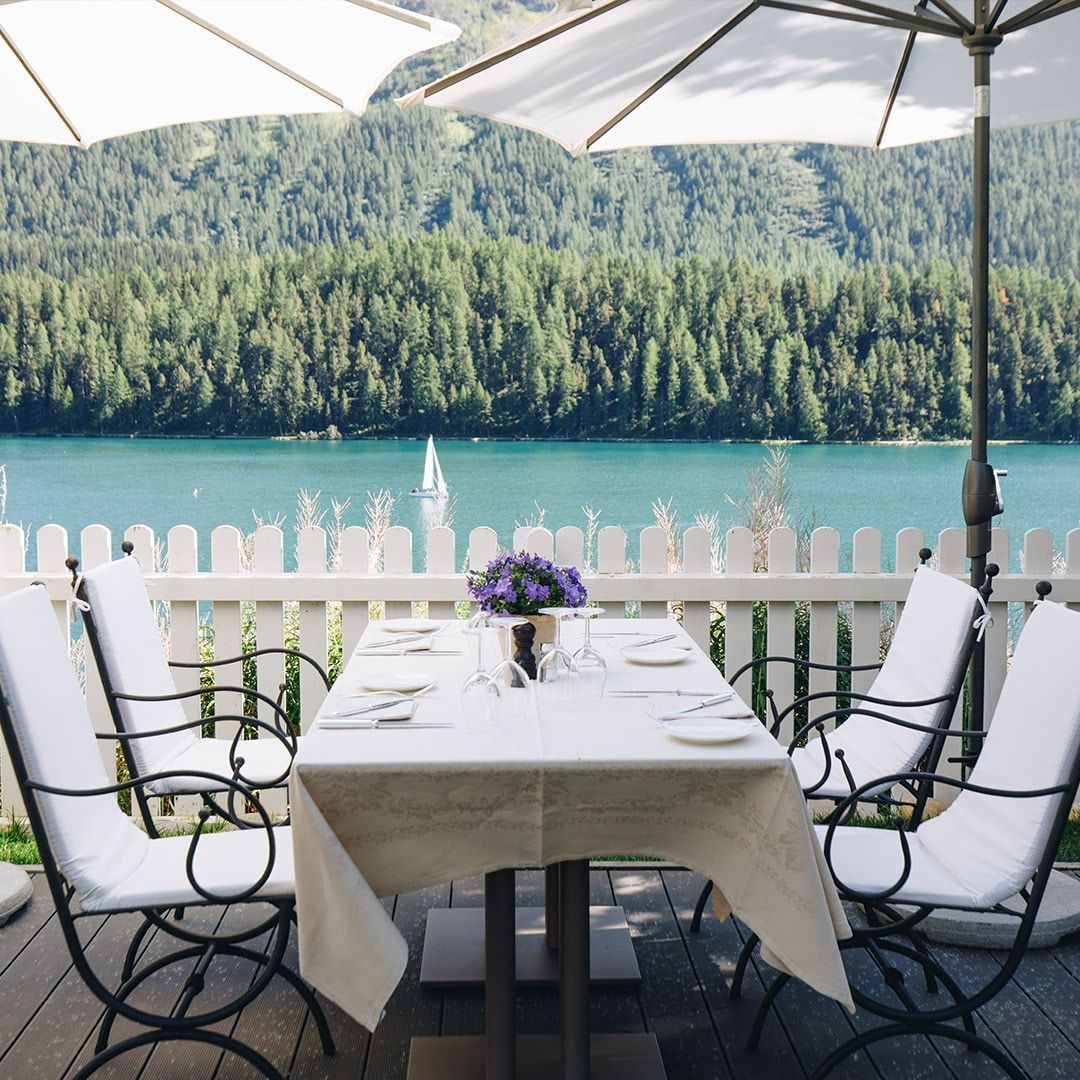 Outdoor dining table set for a meal with a lake and forest view.