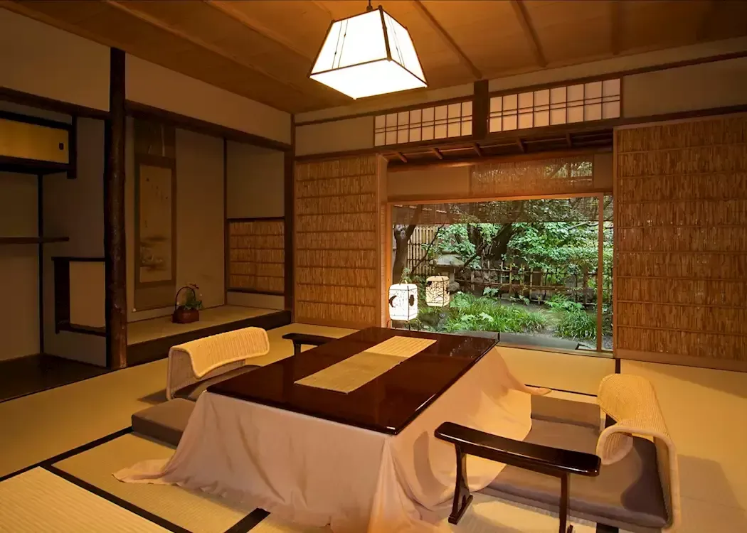 Japanese-style room with a low table, tatami mats, and an open view of lush greenery. Tawaraya Ryokan