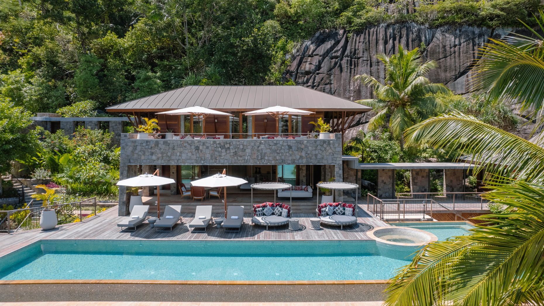 Luxury villa with a pool, deck, and ocean view, surrounded by lush vegetation. The Four Seasons Resort, Seychelles: Paradise on Earth