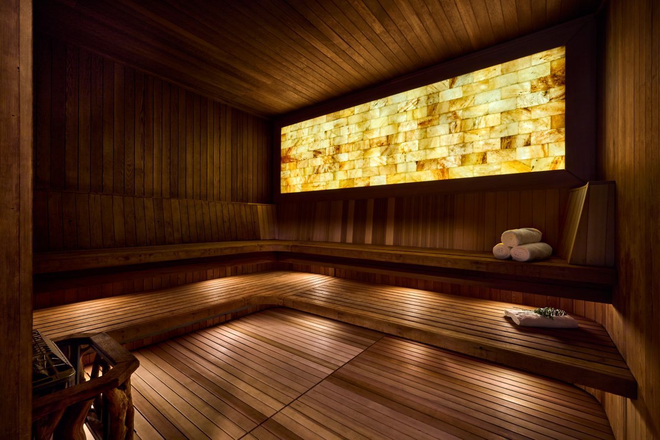 Wooden sauna with glowing salt wall, benches, and soft lighting. The Ritz-Carlton, Half Moon Bay, California