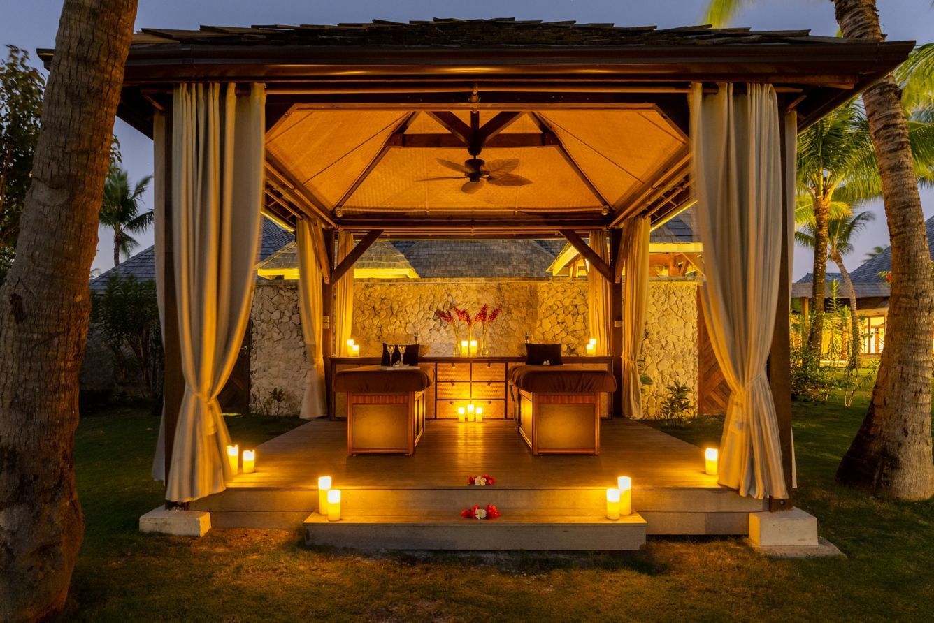 Outdoor spa with two massage tables, candles, and draped curtains at night. The St. Regis, Bora Bora