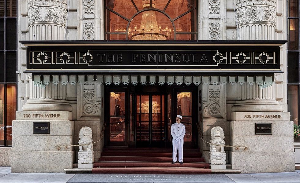 Entrance to The Peninsula hotel on 5th Avenue, NYC. Doorman stands at the entrance under the awning.