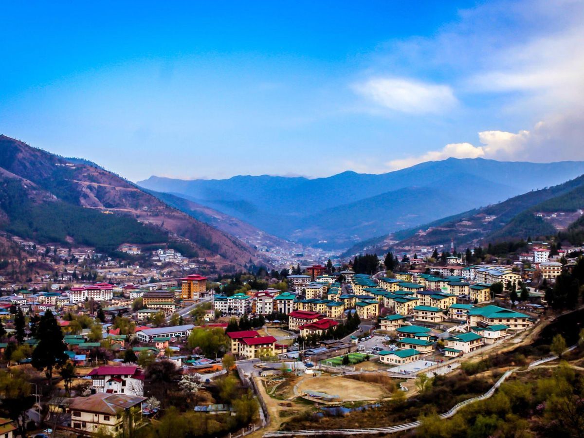 Cityscape nestled in a valley with mountains in the background, Bhutan. Buildings with colorful roofs.