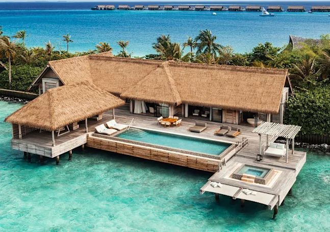 Overwater villa with a thatched roof, private pool, and jacuzzi in turquoise ocean. Waldorf Astoria Maldives Ithaafushi