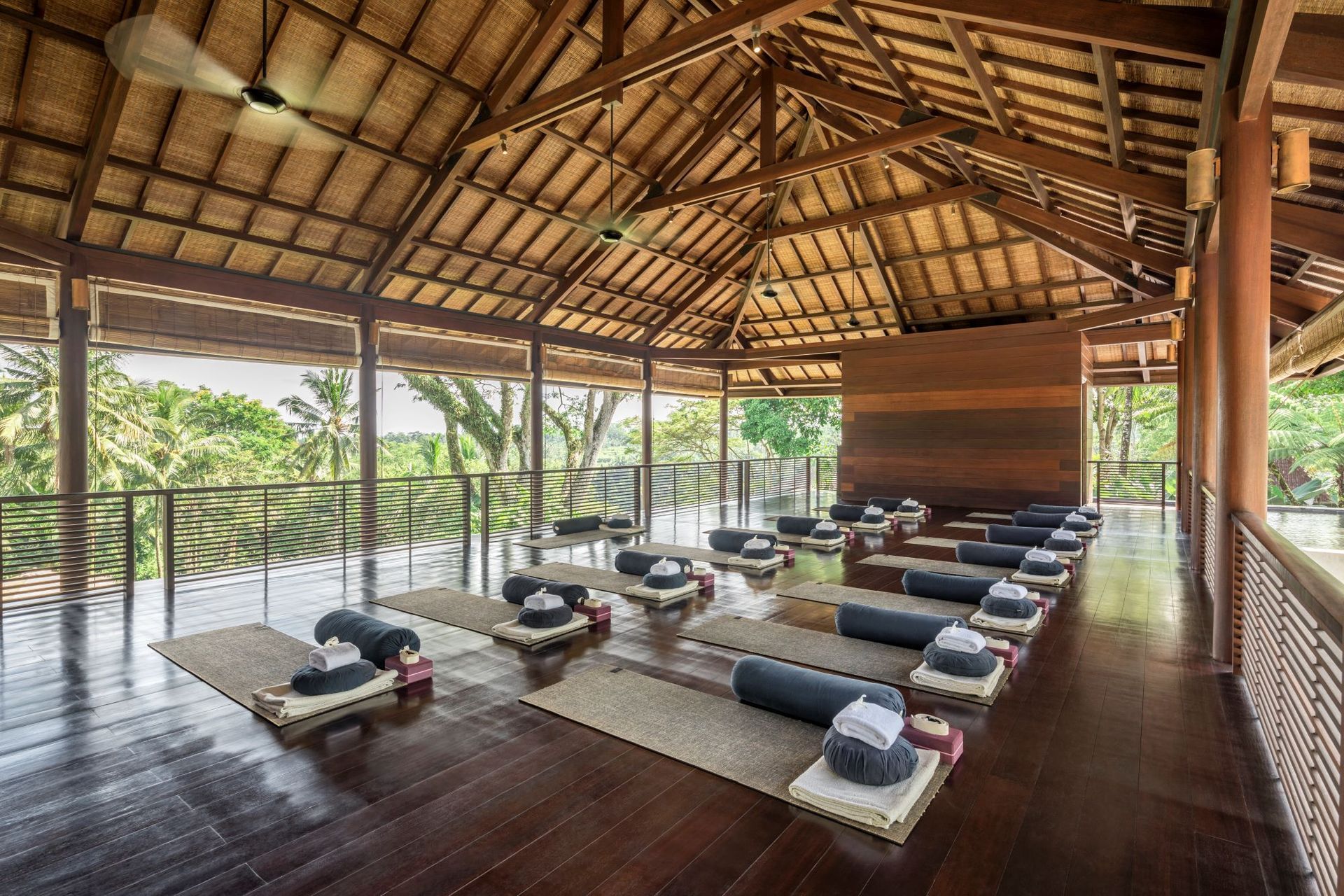 Yoga studio: open-air, wooden structure with mats and props. Overlooking greenery; natural light.