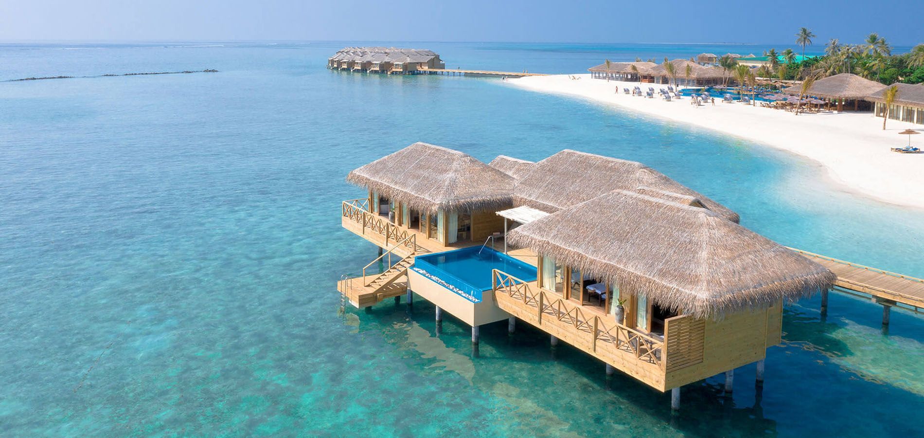 Overwater bungalows with thatched roofs, turquoise water, white sand beach, tropical resort. You & Me Maldives