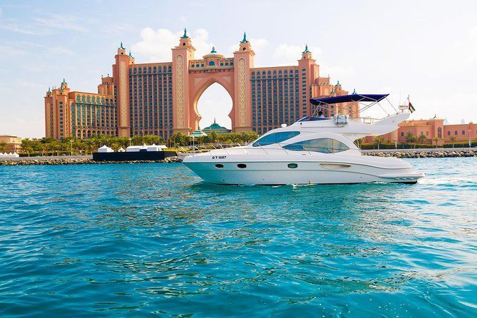 White yacht in turquoise water, with the Atlantis hotel in the background, Dubai.