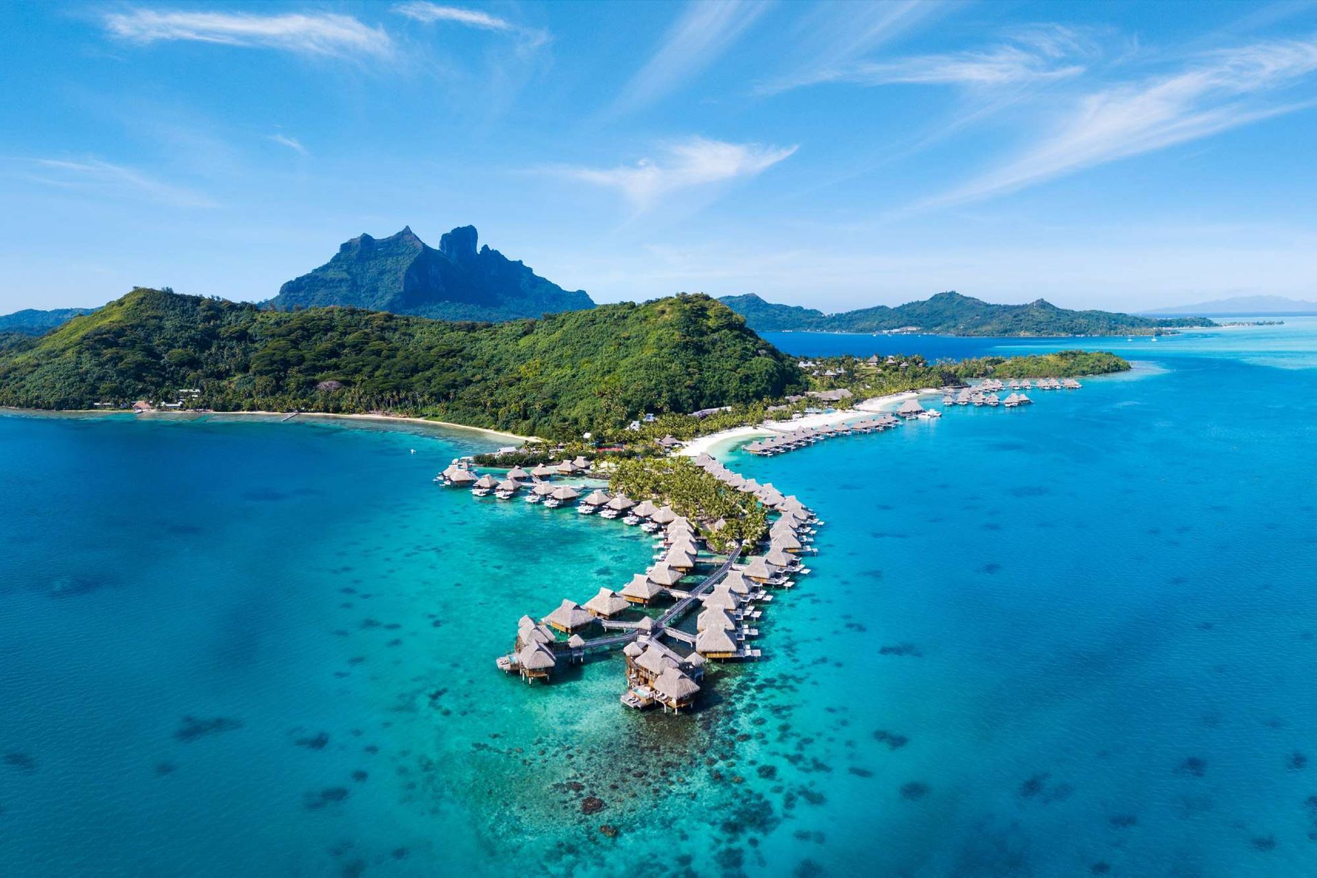 Tropical island with turquoise water, overwater bungalows, and a green mountain backdrop. Bora Bora French Polynesia