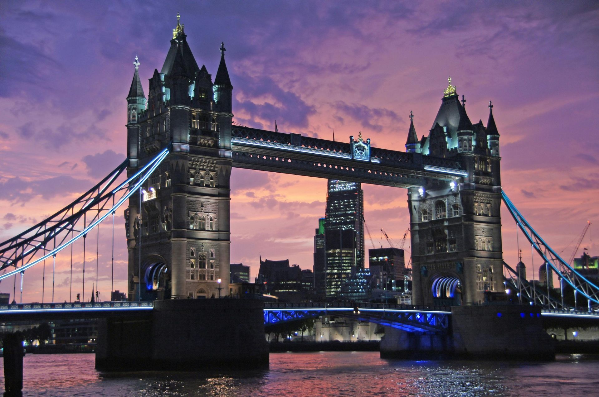 Tower Bridge, London at dusk; lit up against a purple and orange sky.