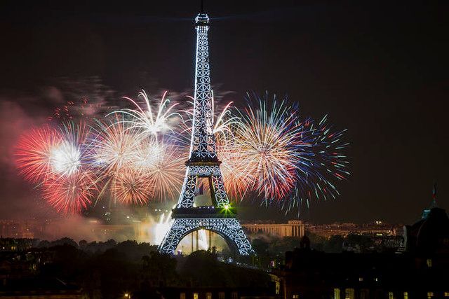 Eiffel Tower illuminated at night with fireworks exploding in the sky.