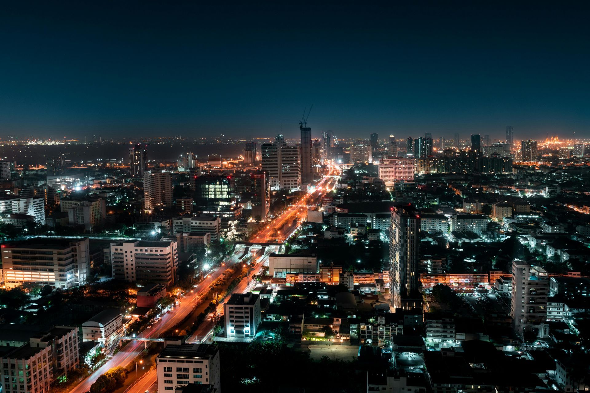 Nighttime cityscape with glowing streetlights and buildings under a dark blue sky.