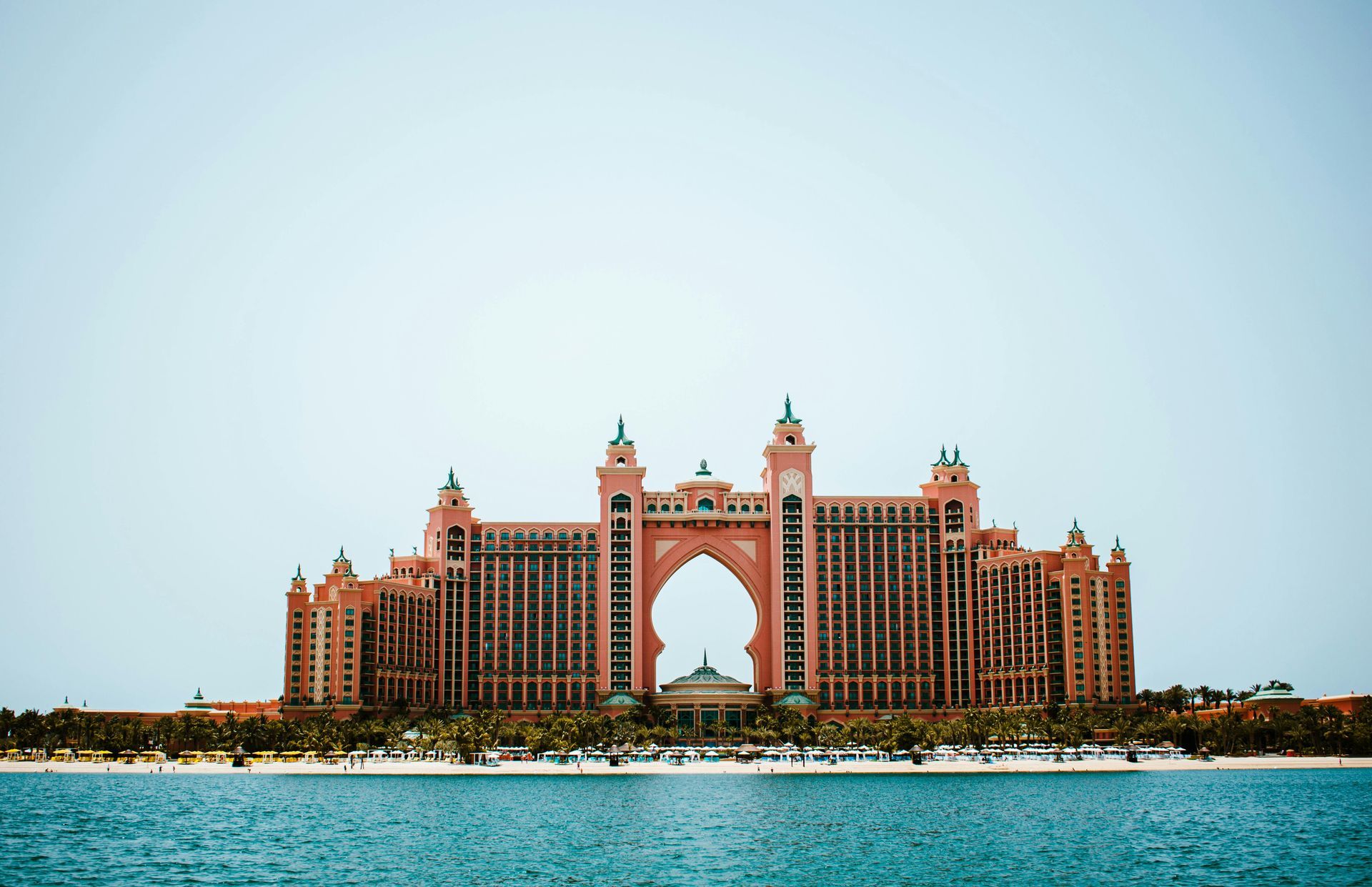 Atlantis resort in Dubai, pink and beige architecture with a large archway against a clear sky.