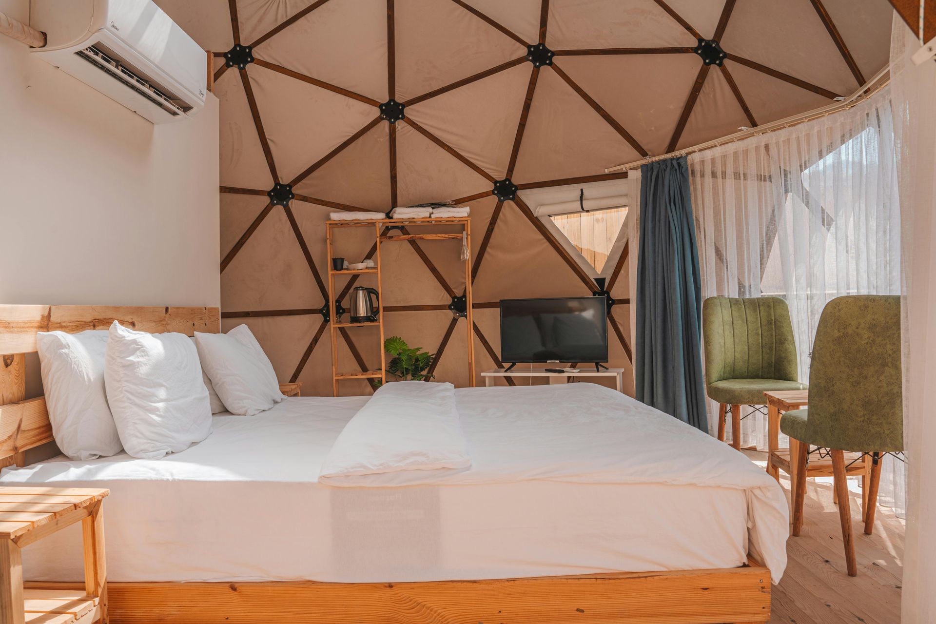 Bedroom with a wooden bed, geometric wall design, TV, and green chairs.