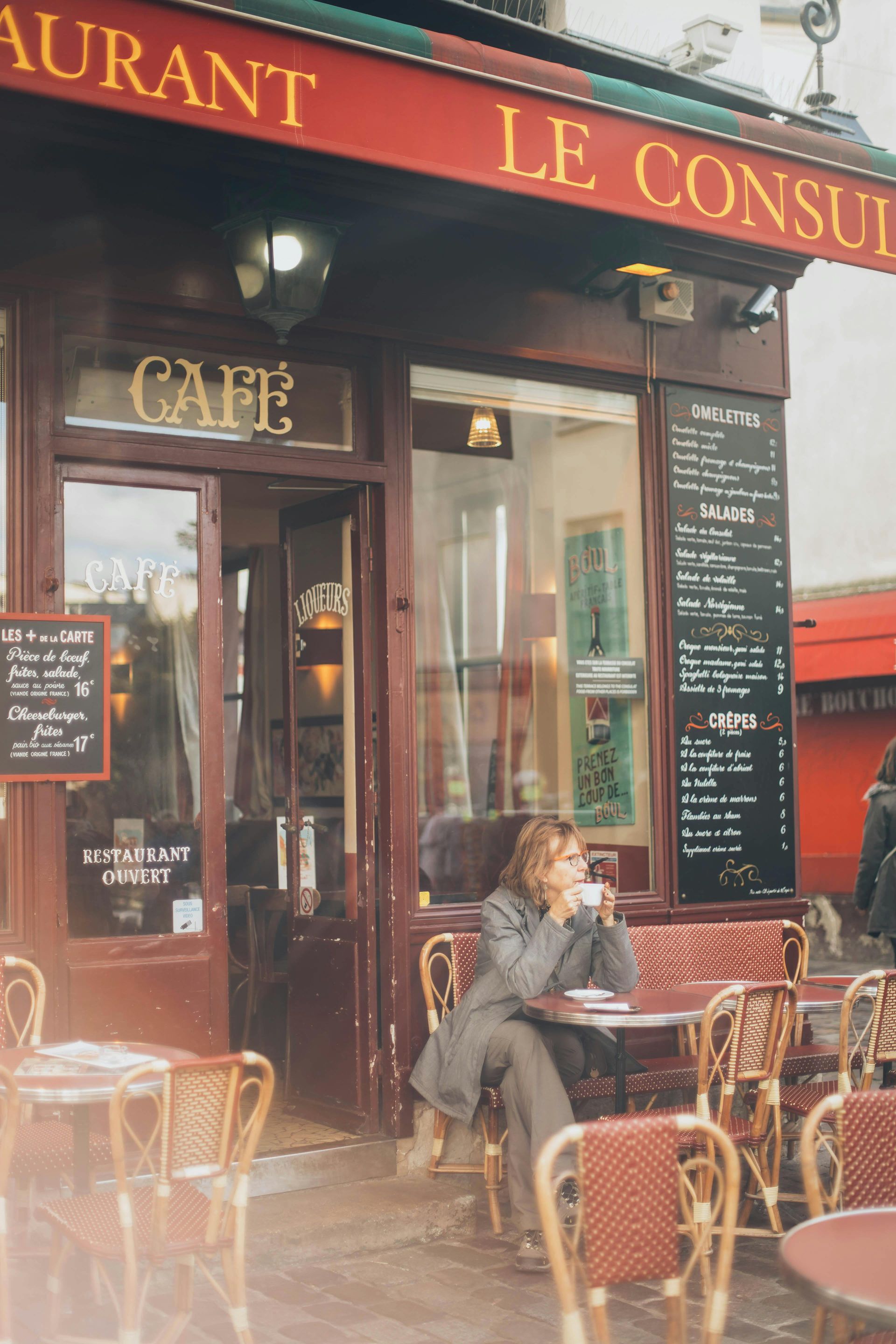 Woman seated at a cafe table outside