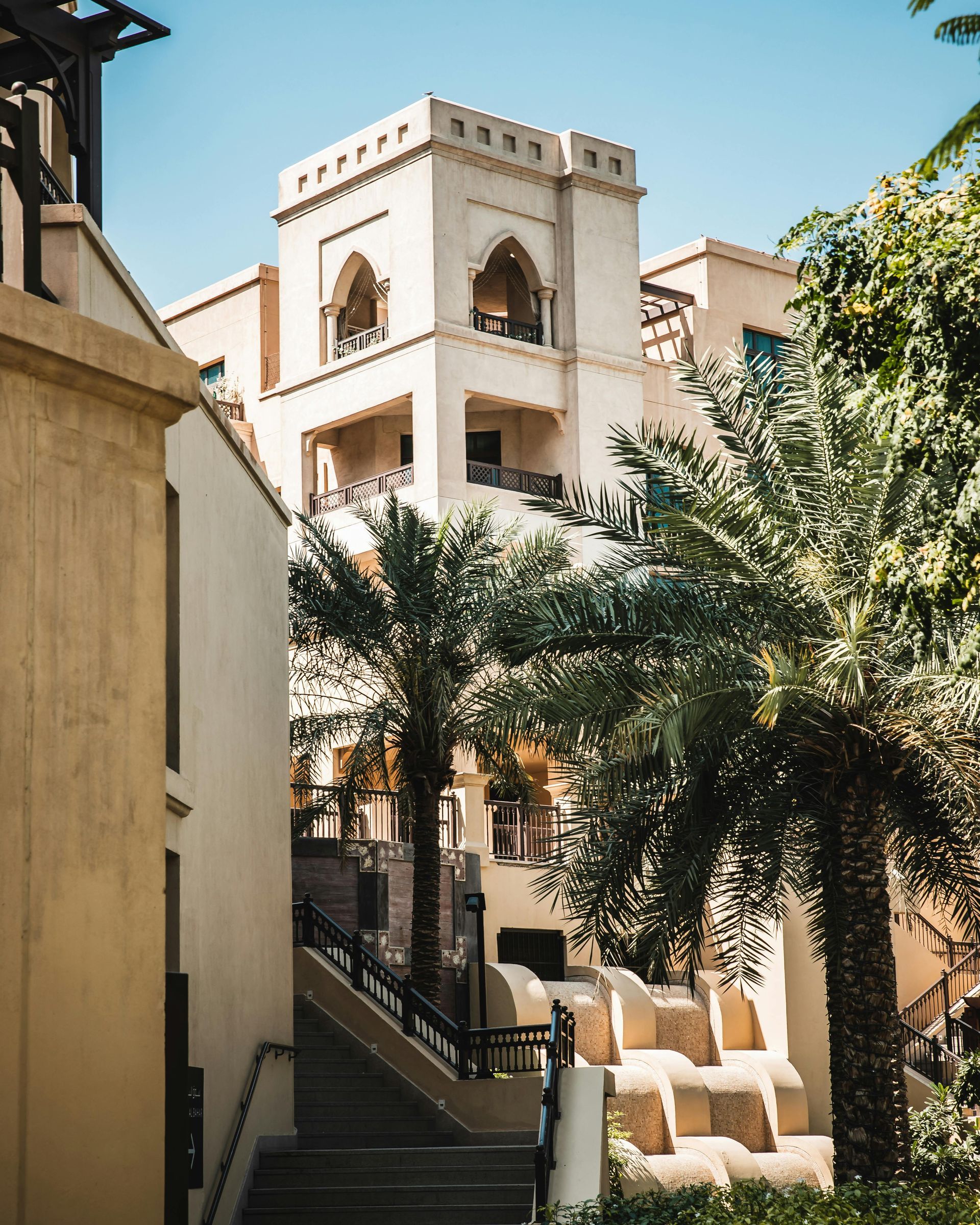 Beige Middle Eastern architecture with palm trees and a pathway.
