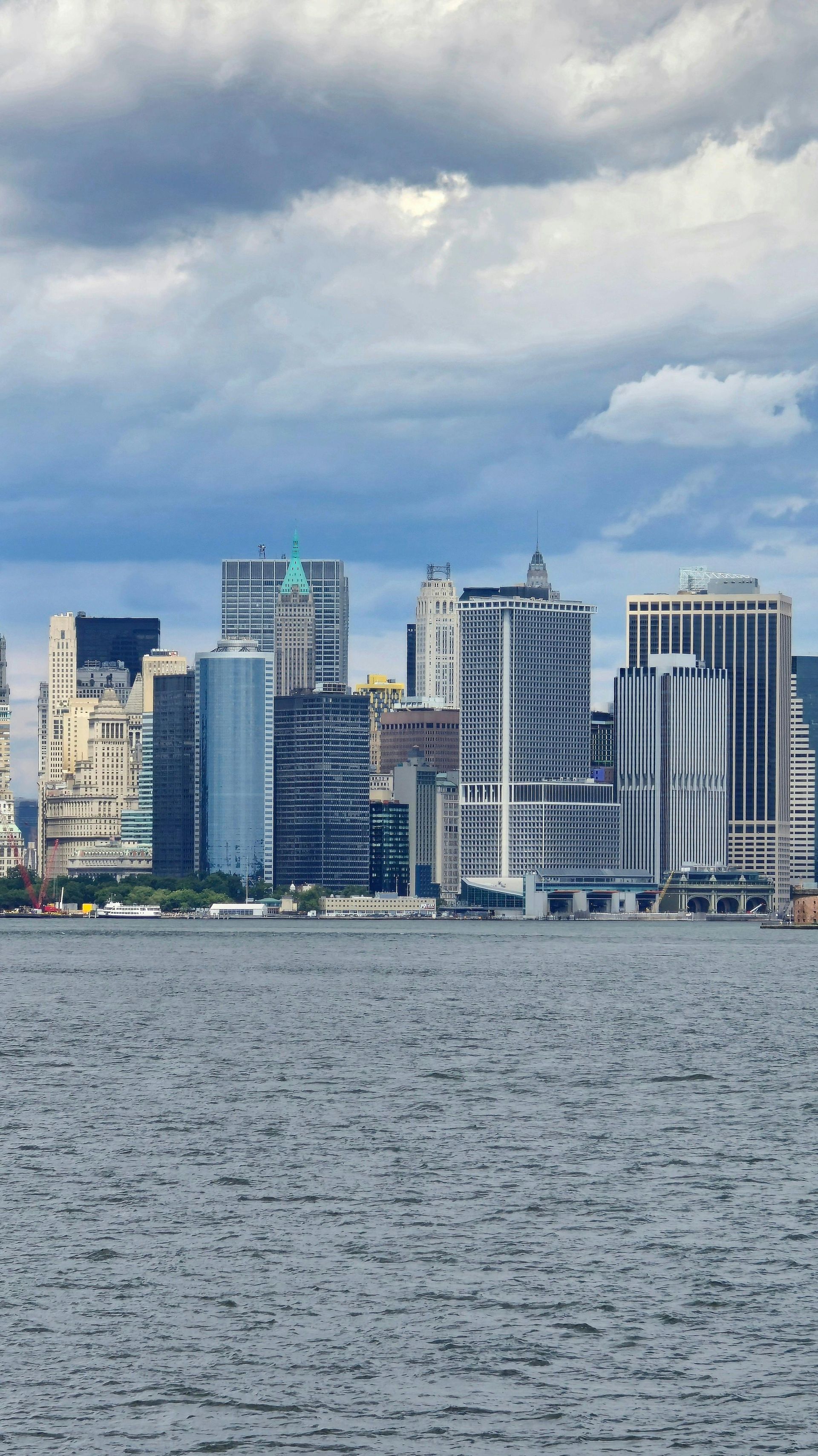 City skyline along a body of water under a cloudy sky.